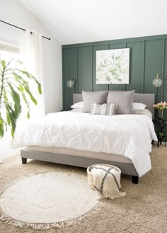 a bedroom with green walls and white bedding, carpeted flooring and rugs