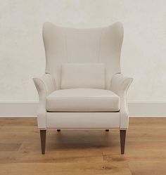 a white chair sitting on top of a hard wood floor in front of a wall