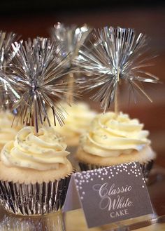 some cupcakes with white frosting and silver sprinkles on them