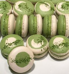 green and white macaroons with sprinkles on them are arranged in rows