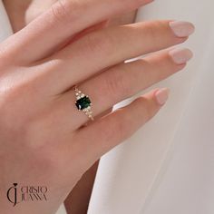 a woman's hand with a ring on it and a green stone in the middle