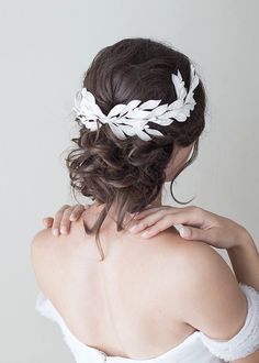 a woman with her back to the camera, wearing a white wedding hair piece that has leaves on it