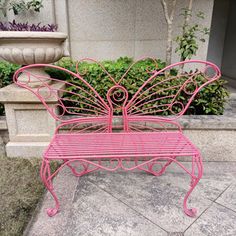 a pink metal bench sitting next to a planter