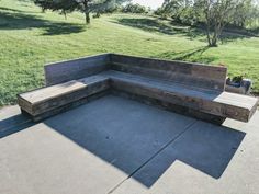 a wooden bench sitting on top of a cement ground next to a green grass covered field