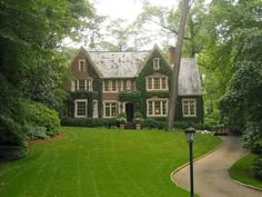 a large house in the middle of a lush green yard with a lamp post and walkway leading to it