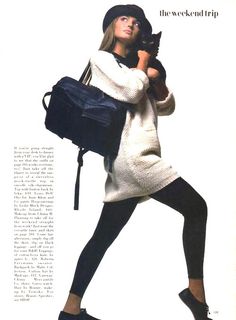 a woman is holding a cat and posing for a magazine ad with her handbag