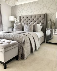 a bedroom with a bed, ottoman and chandelier