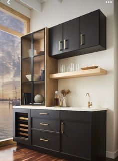 a kitchen with black cabinets and white counter tops next to a large window overlooking the water