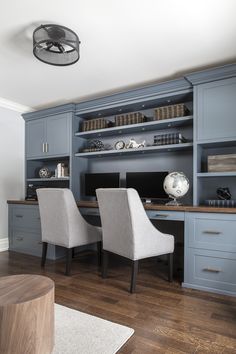 a home office with blue cabinets and white chairs