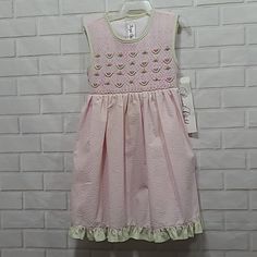 This Little Dress Would Make A Beautiful Addition To Any Child's Wardrobe. It Is Light Pink Trimmed In Pale Green Seersucker. It Has A Smocked Bodice With Pink Watermelons All Across. The Bodice Is Fully Lined. However, The Skirt Is Not. It Is Made In The Philippines Of Soft Searsucker, Sixty Percent Cotton, And Forty Percent Polyester. It Is Machine, Wash Warm With Mild Soap Or Dishergent. Tumble Dry Medium, No Chlorine Bleach. If Necessary, Touch Up With A Cool Iron, Wash Dark Colors Separatel Sleeveless Smocked Bodice Cute Dress, Cute Fitted Sleeveless Smocked Dress, Cute Sleeveless Smocked Dress For Spring, Cute Sleeveless Cotton Smocked Dress, Playful Pink Dress With Smocked Bodice, Pink Cotton Smocked Bodice Dress, Playful Pink Smocked Dress For Summer, Cute Pink Cotton Smocked Dress, Pink Smocked Sundress With Smocked Back