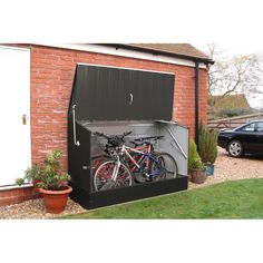 two bikes are parked in the back of a storage shed that is open to reveal a car