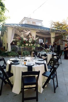 an outdoor dining area with white table cloths and black chairs