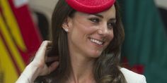 a woman in a white dress and red hat smiles at the camera while sitting down