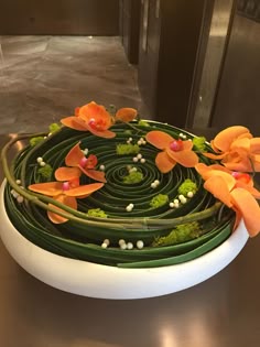 flowers are arranged on top of each other in the center of a circular bowl that sits on a table