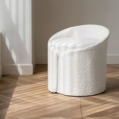 a white stool sitting on top of a hard wood floor next to a wall and window