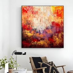 an abstract painting hangs on the wall above a modern chair and table in a living room