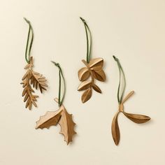 three wooden ornaments with leaves and acorns hanging from strings on a white surface