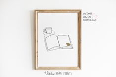 an open book with a coffee cup on it is hanging in front of a white wall