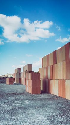 a large group of wooden blocks sitting on top of a dirt field under a blue sky