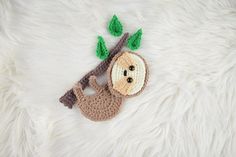 a crocheted monkey hanging from a tree branch on a white furnishing