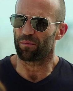 a bald man wearing sunglasses looking at the camera