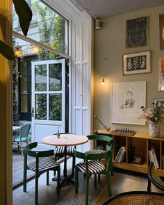 a table and chairs in a room with pictures hanging on the wall above it's windows