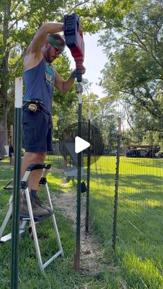 a man on a ladder working on a fence