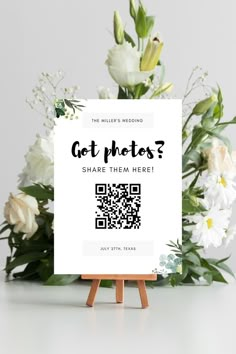 a sign that says got photos? share them here with white flowers in the background