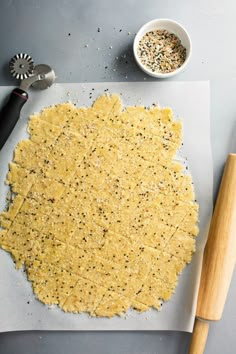 an uncooked pizza crust on a cutting board next to a bowl of seasoning