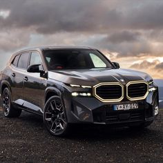 the bmw concept suv is parked on top of a hill with dark clouds in the background