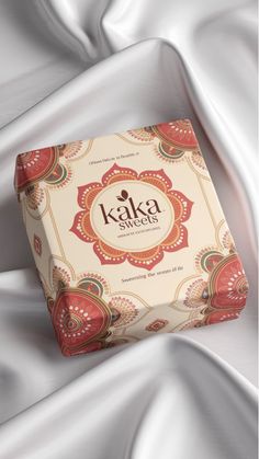 a box of kaka chocolates sitting on top of a white cloth covered bed