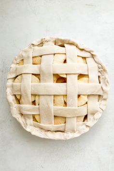 an uncooked apple pie on a white surface