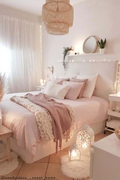 a bedroom with white walls and pink bedding in the center is lit by candles