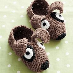 two crocheted slippers with eyes and nose are sitting on a polka dot tablecloth