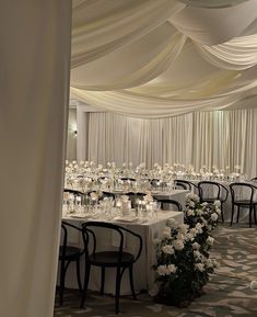 a banquet hall with tables and chairs covered in white draping