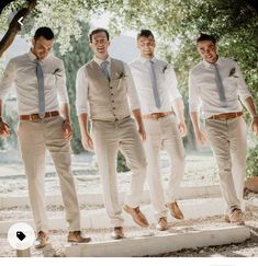 a group of men standing next to each other on top of a cement slab in front of trees