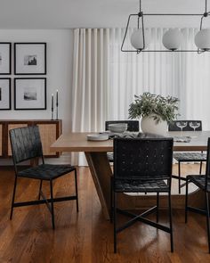 a dining room table with chairs and pictures on the wall behind it in front of a window