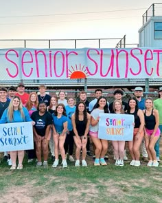 a group of people holding up signs in front of a fence with the words senior sunset written on it