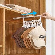 a person is holding a baseball cap on a rack with other hats hanging from it