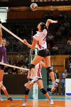 two women playing volleyball on an indoor court