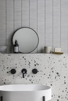 a white sink sitting under a round mirror