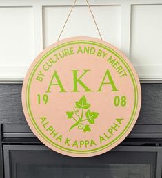 a pink and green sign hanging from the side of a wall next to a fireplace