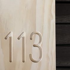 a close up of the number thirteen on a door with wood panels in the background