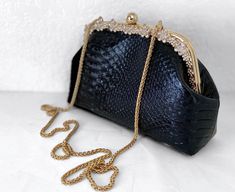 Dimension: Length(10in) x Width(3in) x Height(6.5in) A beautiful stylized purse/handbag which is unique and currently in fashion. The purse/handbag is black pleather. The bag has an gold colored spherical bead closure. The mouth of the closure has a decorative goldish color with a floral rhinestone embellishment pattern. The purse has an added feature that allows the owner to carry it as a purse/handbag or use the chain to wear it draped on the shoulder. It looks stylish. It is medium in size. T Wedding Handbag, Favorite Purse, Jeans For Girls, Floral Handbags, Shoes For Summer, Wedding Purse, Golden Design, Purse Gift