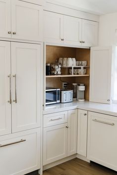 a kitchen with white cabinets and appliances in it