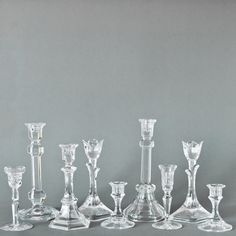 an assortment of glass candlesticks on a gray background