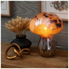 a lamp that is sitting on top of a table next to a vase with dry grass in it