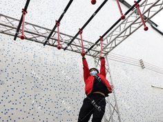 a man in red jacket standing on top of a metal ladder next to blue and white tiled wall