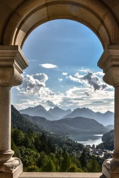 the view from an arch in a building overlooking mountains and trees, with water below