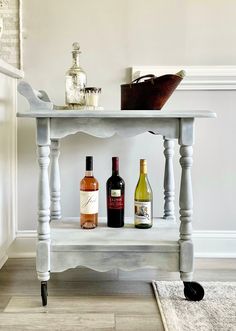 a white table with bottles of wine on it and a rug in front of it